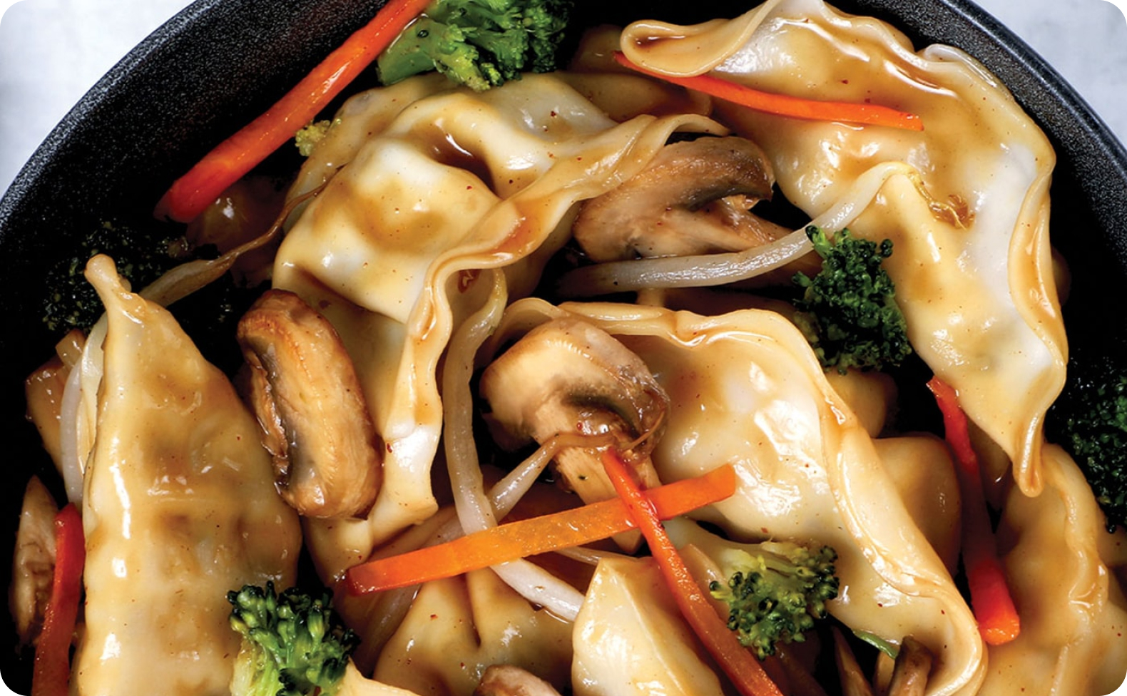 Stir fry containing a combination of dumplings, broccoli, mushrooms and carrots.