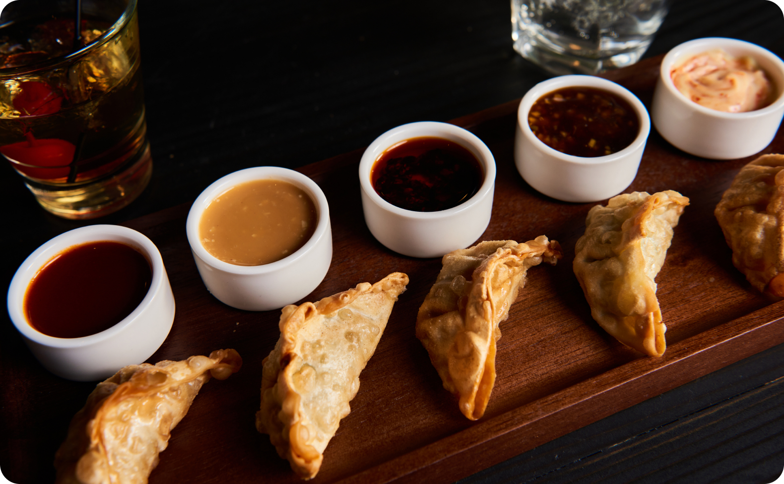 Tray of dumplings with a variety of dipping sauces.