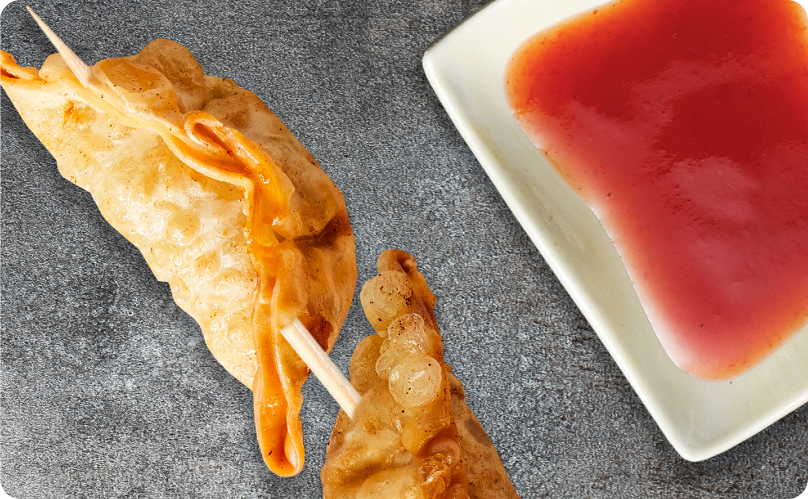Fried dumplings on a skewer accompanied with dipping sauce.
