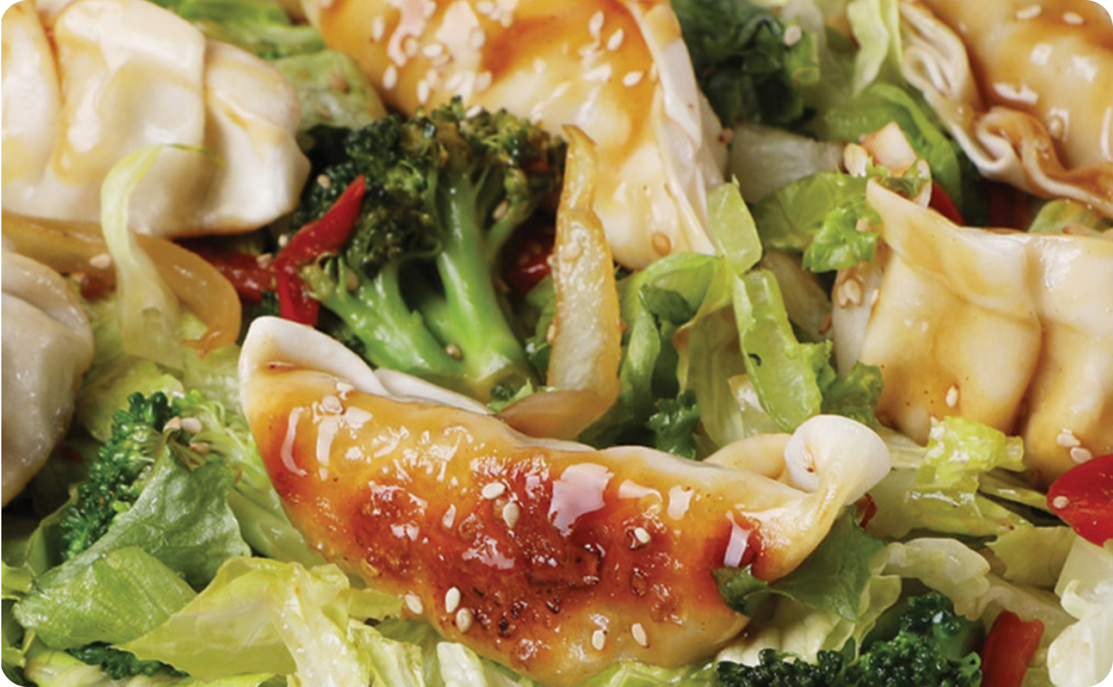 Salad containing a combination of dumplings, lettuce, broccoli, bell pepper and onion.